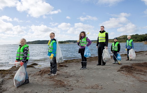 Children wearing hi-vis jackets collecting rubbish on the beach.